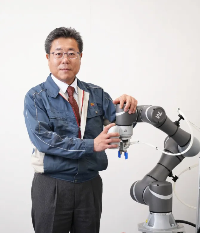 協働ロボットと並ぶ代表取締役社長の写真