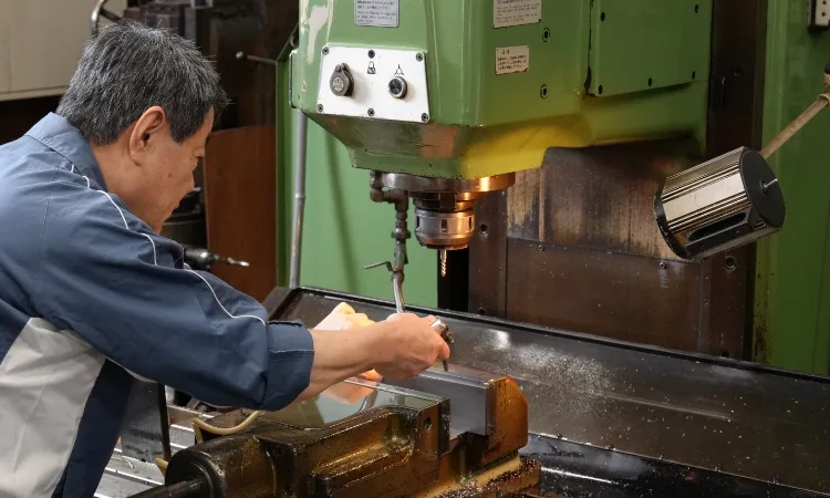 工場内で金属加工機械を操作する作業員の写真